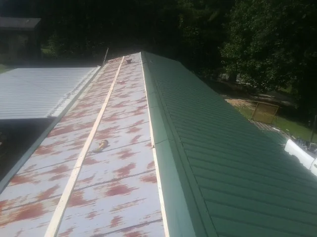 Old rusted panels beside newly installed green metal roofing — Wind Damage Roof Repair by Roofing Brothers in Louisville