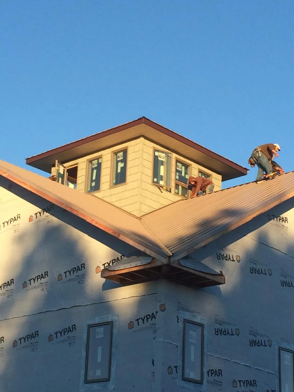 Roofers working around a rooftop cupola on a new metal roof at sunset — Roof Waterproofing in Louisville by Roofing Brothers